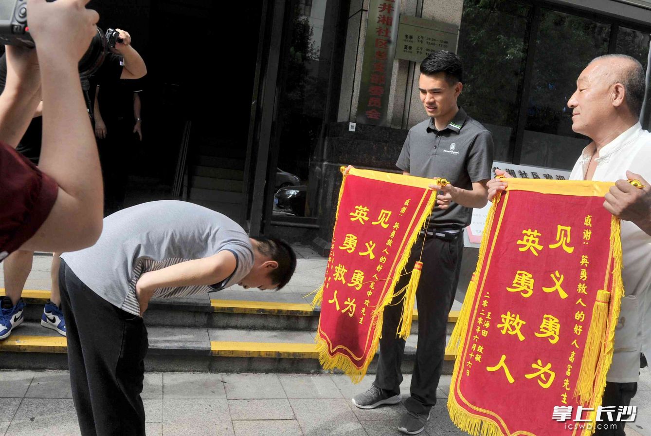 被救男孩的父亲给救上自己儿子的龙中欢（右二）和高富（右一）送上锦旗以示感恩。长沙晚报全媒体记者 贺文兵 摄