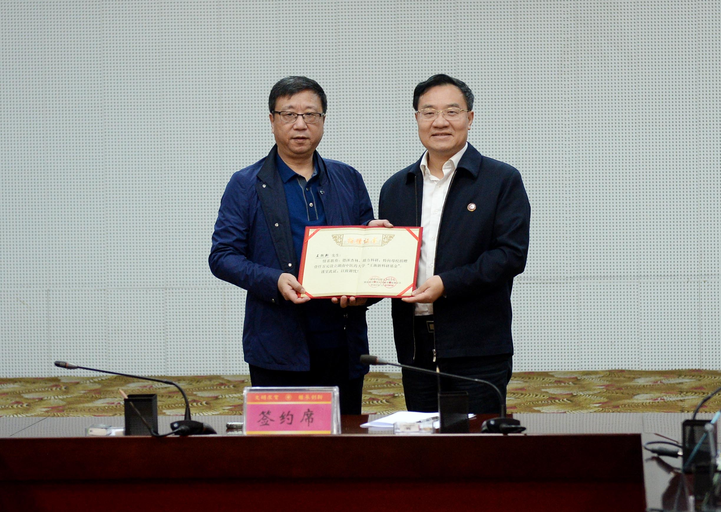 湖南中医药大学党委书记秦裕辉(右)为79级校友王衡新颁发荣誉证书。长沙晚报全媒体记者石祯专 摄 湖南中医药大学党委书记秦裕辉(右)为79级校友王衡新颁发荣誉证书。长沙晚报全媒体记者石祯专 摄