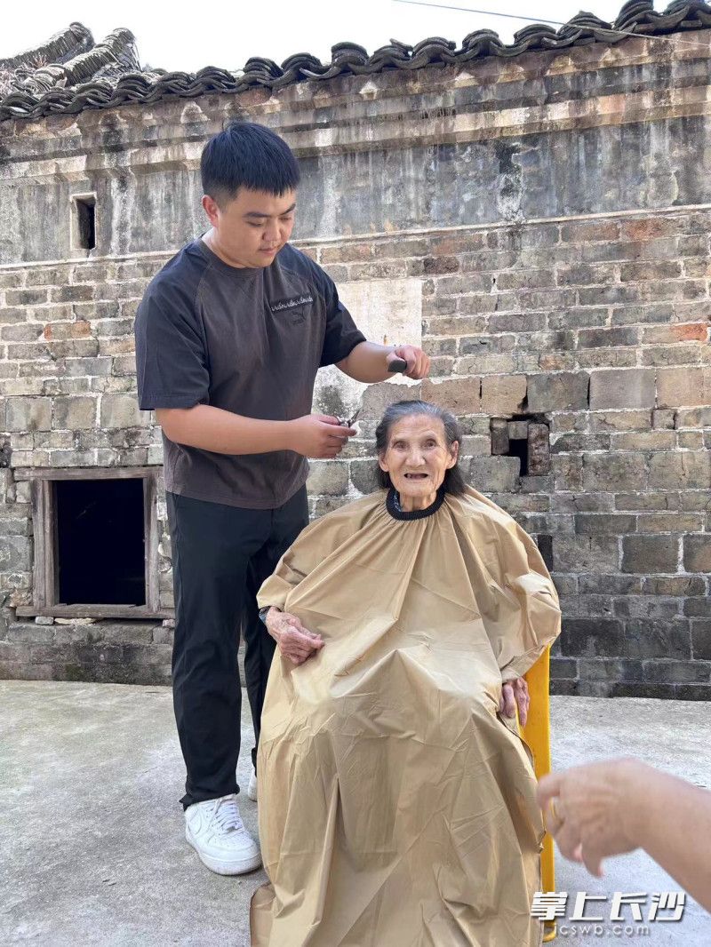 杨壮壮在为谢淑君老人理发。