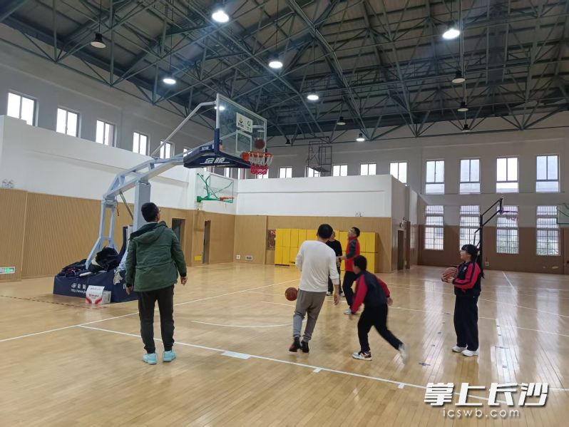 长郡月亮岛学校小学部室内体育馆，几名家长正带着孩子在打篮球。均为长沙晚报全媒体记者 陈良 摄