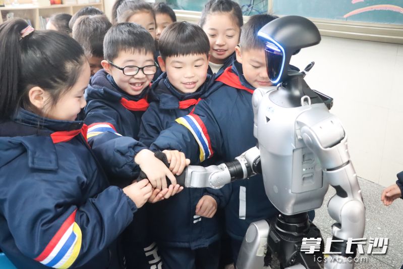 同学们纷纷与机器人握手。 同学们纷纷与机器人握手。