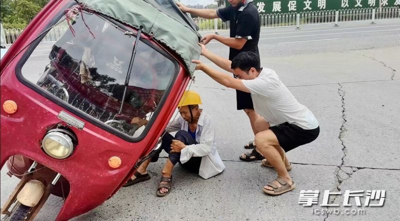 葛鹏与路人合力抬起三轮车将被困老人救出。 受访者供图 葛鹏与路人合力抬起三轮车将被困老人救出。 受访者供图