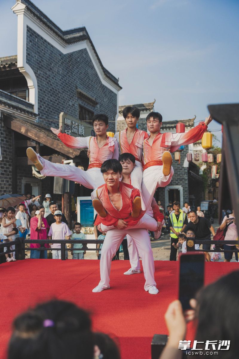 古街戏台之上,杂技演员层层叠起,亮出精彩技艺。 古街戏台之上,杂技演员层层叠起,亮出精彩技艺。