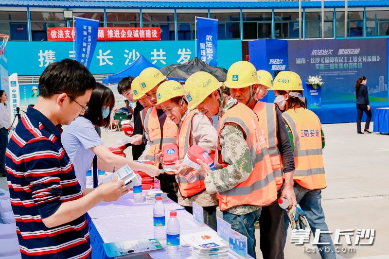 宣传人员为农民工解读《条例》。 宣传人员为农民工解读《条例》。